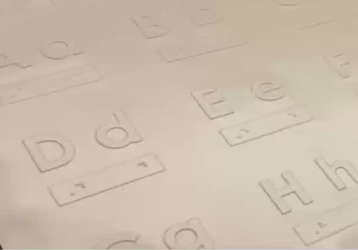 Folha plástica com as letras do alfabeto em relevo e a respetiva correspondência em Braille