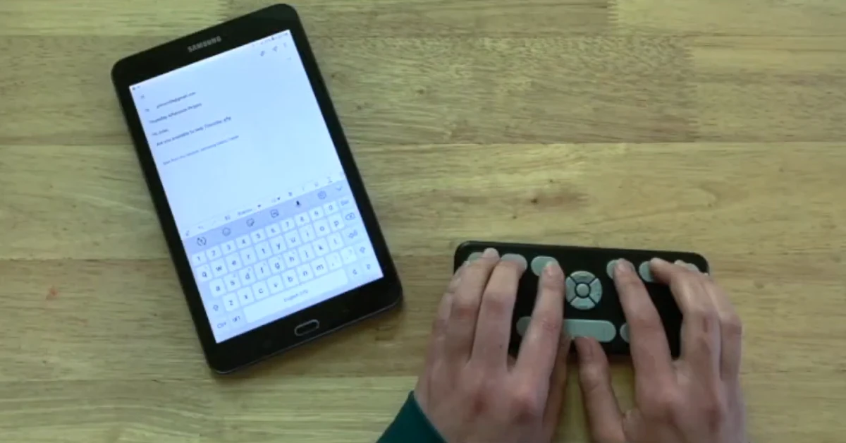 Pessoa utilizar o teclado Braille Orbit Writer com um tablet em cima de uma mesa